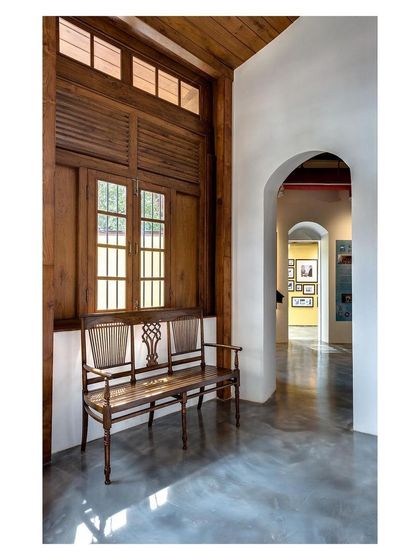 Inside the restored museum, an antique bench sits within a deep-set window alcove. This moment captures the dialogue between the building's colonial past and its new purpose, preserving original features like the wooden windows.
