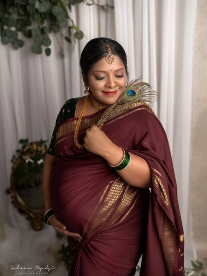 A touch of divinity with a peacock feather. This pose is full of grace, as the mom-to-be connects with her baby in a setting that feels both traditional and serene.