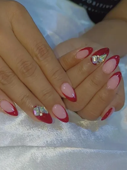 A classic red French manicure made even more glamorous with statement butterfly rhinestones on the accent nails.