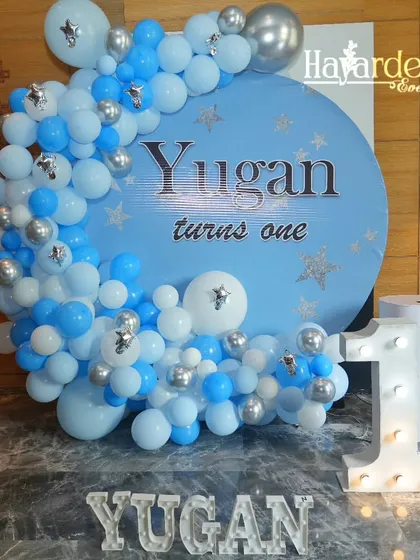 A 'Twinkle Twinkle Little Star' theme for a first birthday. The blue and silver balloon garland on a circular backdrop is paired with a marquee number '1'.
