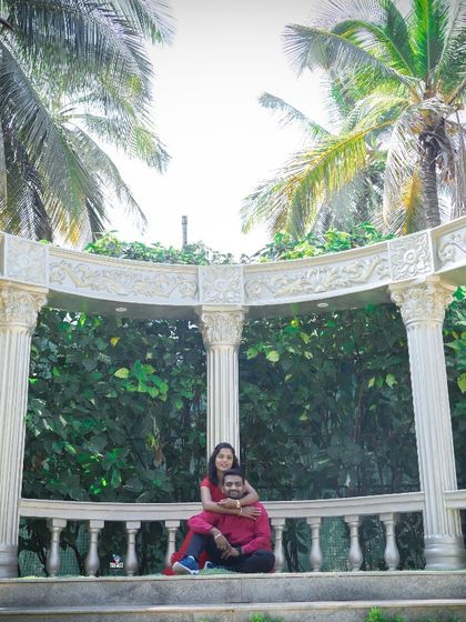 This couple looks serene and happy in a beautiful white gazebo, surrounded by lush greenery. A classic and elegant studio set for pre-wedding photos.
