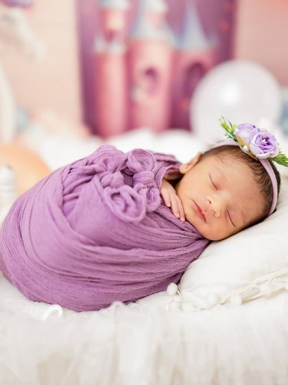 A precious newborn girl wrapped in a lovely lavender swaddle, complete with a matching floral headband. I have swaddles in every color to match your vision.