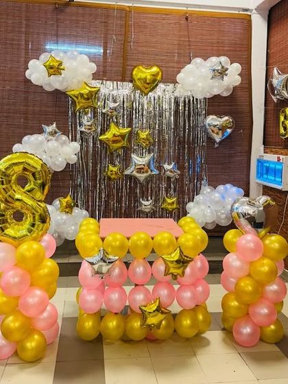 A pink and gold star-themed 8th birthday setup with a balloon-wrapped cake table.