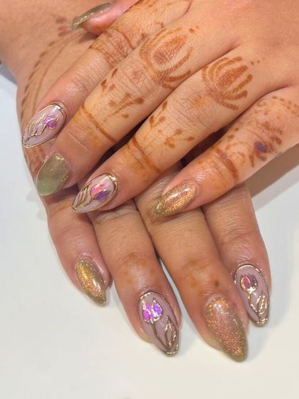 An exquisite nail design that perfectly complements traditional henna. This look features a gold chrome base with delicate, hand-painted floral art, creating a luxurious and cohesive style.