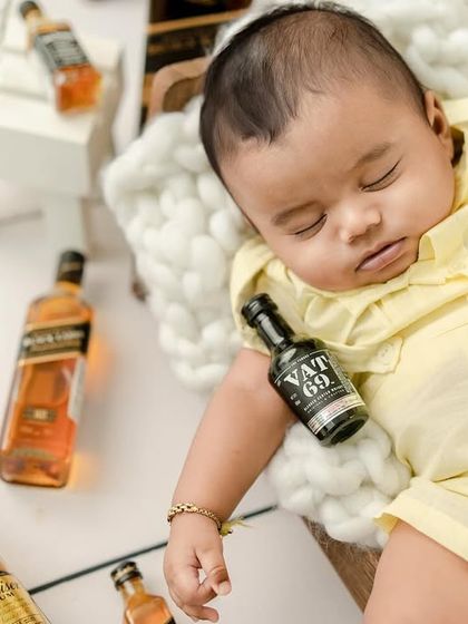 Passed out after a wild party. The tiny prop bottles and sleeping pose make this a hilarious and unforgettable baby portrait.
