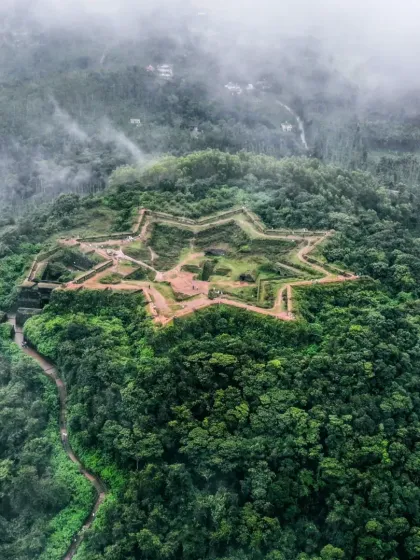 A stunning photograph of the star-shaped Manjarabad Fort in Sakleshpur, completely surrounded by the lush green forest of the Western Ghats.