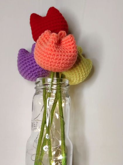 A closer look at the colorful crochet tulips in a jar with fairy lights.