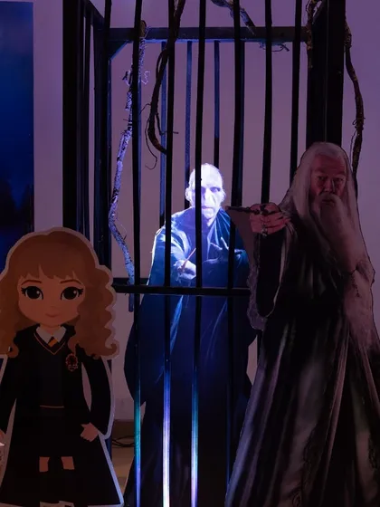 A spooky setup from a Harry Potter party, featuring cutouts of Voldemort, Dumbledore, and Hermione in a dimly lit, dramatic scene.
