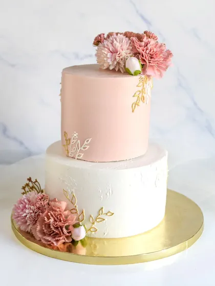 A lovely two-tiered cake perfect for an engagement or intimate wedding. The design combines a textured white bottom tier with a smooth pink top tier, accented with delicate stenciling and fresh carnations.