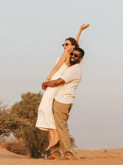 A joyful lift against the clear desert sky, capturing a moment of pure happiness and carefree love during their destination pre-wedding shoot.