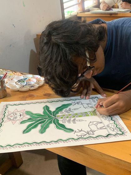 A student's Madhubani artwork capturing the essence of daily life with motifs of the sun, a banana plant, and animals. This art form is deeply connected to nature.