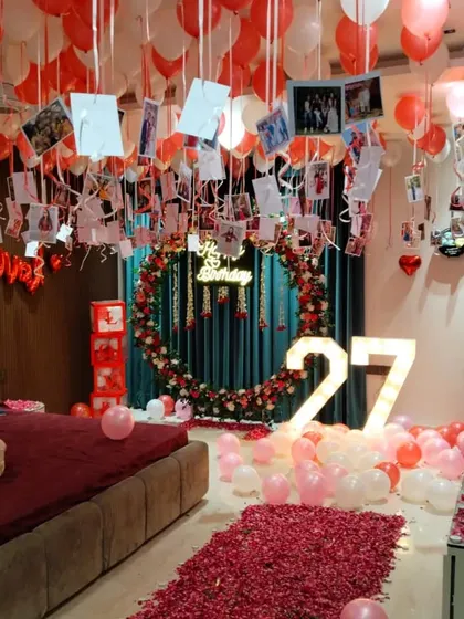 I can create romantic and surprising birthday decorations right in your bedroom. This setup features a floor-to-ceiling display of red and pink balloons, a path of rose petals, a custom floral and balloon ring, and photos hanging from the ceiling to celebrate precious memories.