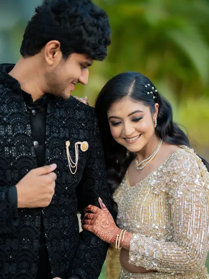 A close-up shot focusing on the couple's happy expressions and the intricate details of their outfits, like the brooch on Apoorv's sherwani.