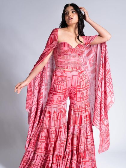 A beautiful pink and red ensemble paired with soft, glamorous makeup. The look features a subtle smokey eye and a neutral lip to balance the bold, printed outfit.