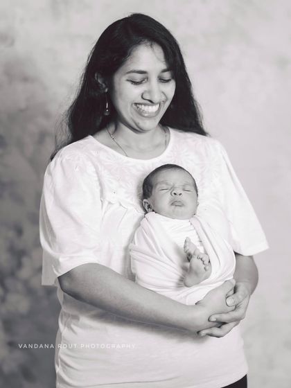 A classic black and white portrait of a mother holding her newborn. The baby's funny little expression and the mother's joyful laugh make this a candid and heartwarming moment that feels incredibly real and full of love.