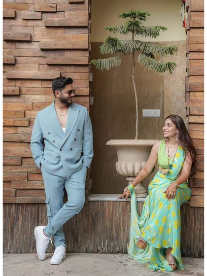 A stylishly composed portrait of the couple against a modern wooden wall. The groom leans casually while the bride sits gracefully, creating a relaxed yet fashionable pre-wedding photograph.