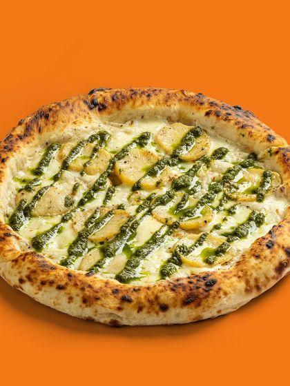 A unique potato and pesto pizza, showcasing an unconventional yet delicious-looking topping combination.