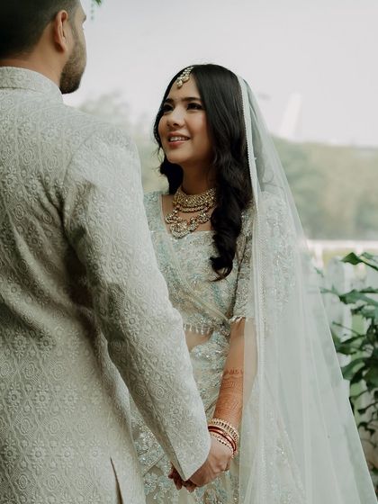 A candid moment between the bride and groom. Her makeup is soft and natural, with beautiful open-hair styling, perfect for a modern wedding ceremony.