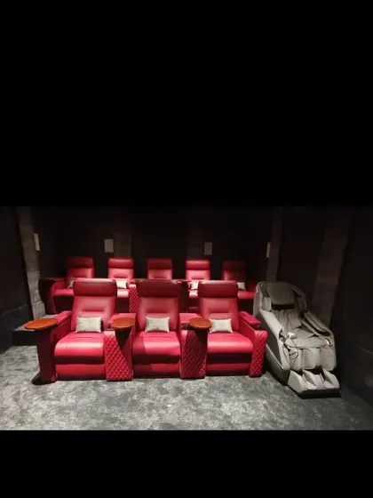 Comfort is key to the cinema experience. We provide custom seating solutions, including these plush, motorized red leather recliners, complete with cup holders and side tables for the ultimate convenience.