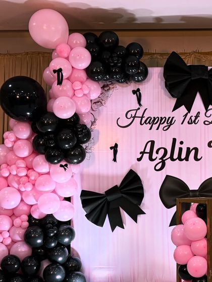 A close-up of the bow-themed backdrop. The combination of black and pink balloons with the custom-made black bows creates a high-contrast, visually appealing design.
