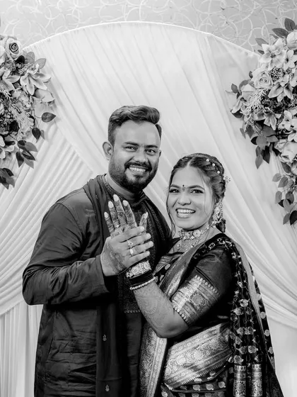 A classic black and white portrait of the happy couple, showing off their rings to the camera.