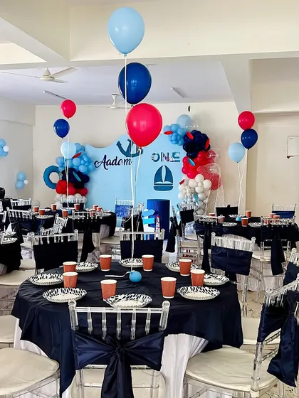 A complete view of the sailor-themed first birthday party we styled. The decor includes navy blue tablecloths, themed paper goods, and balloon centerpieces, creating a cohesive nautical look throughout the venue.