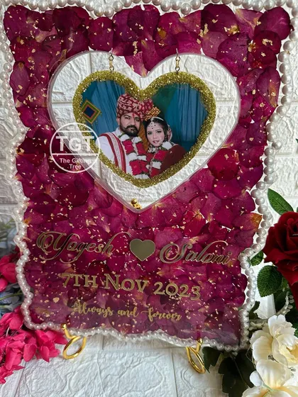 This heart-themed design is perfect for capturing your love story. In this 12x16 inch frame, we set a wedding photo inside a hanging heart cutout, surrounded by a bed of preserved red rose petals from the couple's varmala. The pearl border and gold lettering add a final touch of elegance.