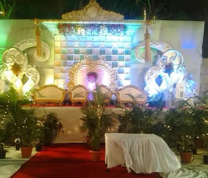 A beautifully lit reception stage in Mumbai with an ornate backdrop and traditional seating for the couple. The combination of fairy lights and colored uplighting creates a magical ambiance for the evening.