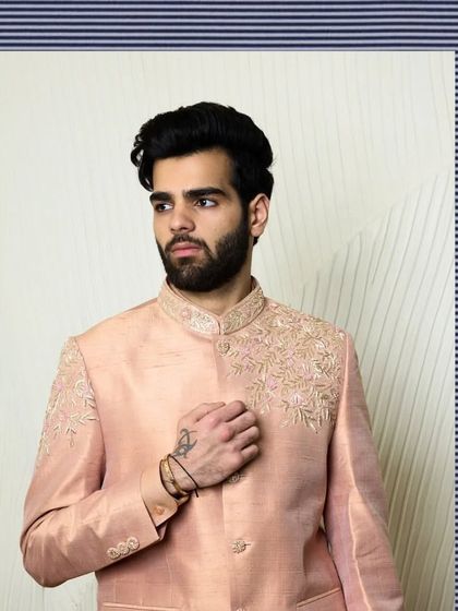 A soft baby pink bandhgala jacket with minimal, elegant threadwork on the shoulders and collar. This piece embodies a blend of subtlety and poise for summer weddings.