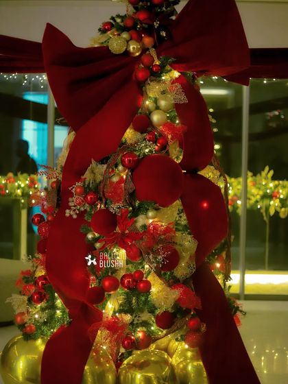 A close-up of the opulent Christmas tree, glowing with warm lights and covered in rich red and gold decorations.