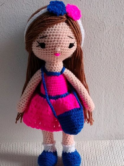 A beautiful doll in a pink dress with a blue bag and matching shoes. I love how the bright colors look together.