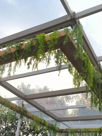 The same pergola with the lights off, showcasing the hanging artificial creepers against the sky.