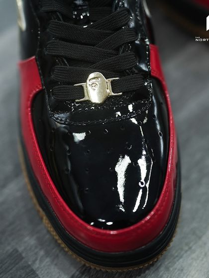 A close-up of the glossy black and red toe box of the Bapesta Dubai Anniversary edition.