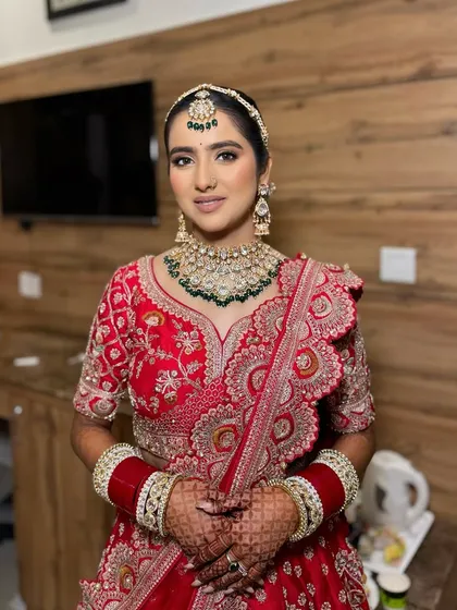 A full view of Simran's stunning bridal look. The classic red lehenga paired with soft, elegant makeup ensures she looks perfect from every angle.