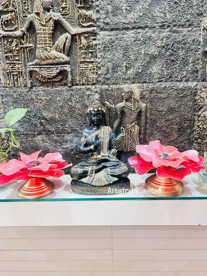 Two floral diyas flanking a Buddha statue, creating a serene and spiritual festive display.