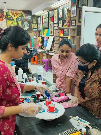 A student carefully pours colored resin during a class, with an instructor guiding her. Our small class sizes ensure personalized attention.