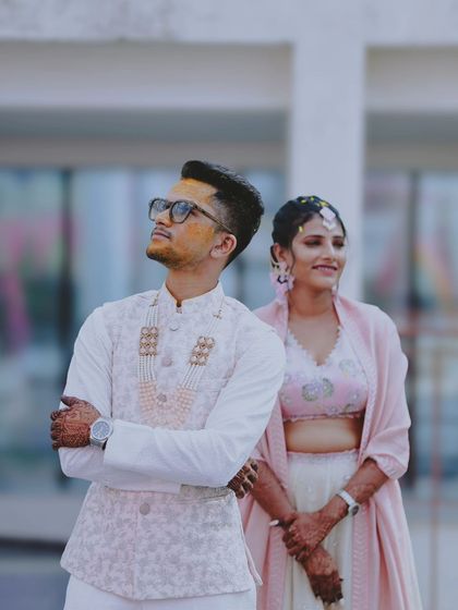 A stylish portrait of a couple during their Haldi ceremony, with turmeric visible on the groom's face.