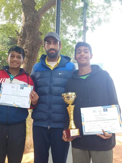 Divyansh Lekhi and another player with their coach after the All India AITA U-14 Tennis Tournament final. Both players hold their trophies and certificates, showcasing a successful event for our academy.