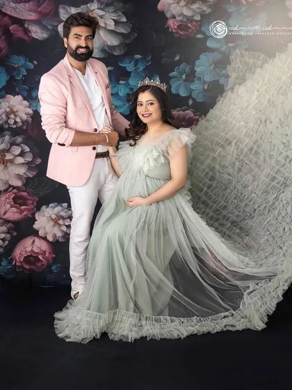 A picture of regal love. The couple stands together, sharing a moment of quiet joy, perfectly complementing the flowing gown and floral background.