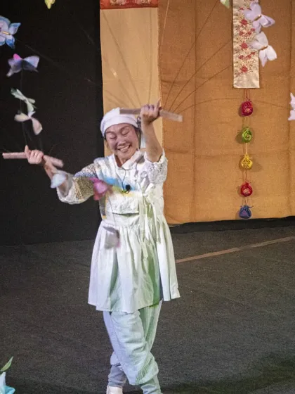 A performer from Korea's 'Puppet Fantasy' joyfully dances with colourful butterfly puppets, creating a whirlwind of motion and happiness.