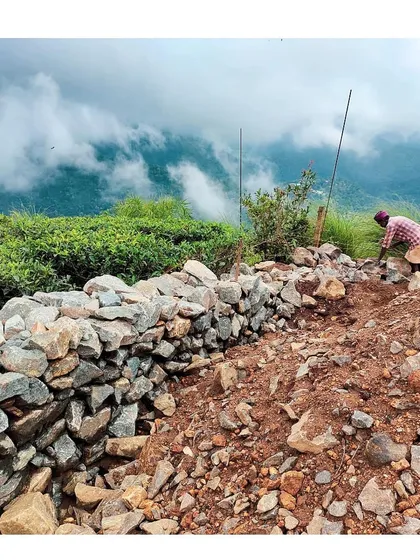 A worker builds a traditional stone retaining wall at the Vagamon site. We often borrow from nature and local building techniques, using materials found on-site to create structures that feel rooted in their environment.