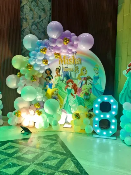 Every girl deserves a princess party. I designed this magical Disney Princess setup with a backdrop featuring all her favorite characters, balloon pillars with princess cutouts, and a light-up number '8' to make her feel like royalty.