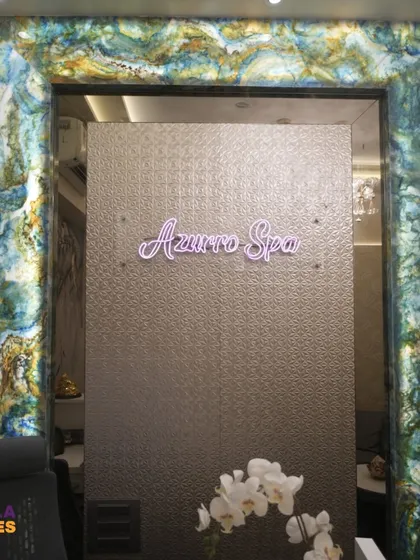 A direct view of the 'Azurro Spa' branding behind the reception. The combination of the textured back wall and the elegant neon sign creates a sophisticated and memorable brand presence.
