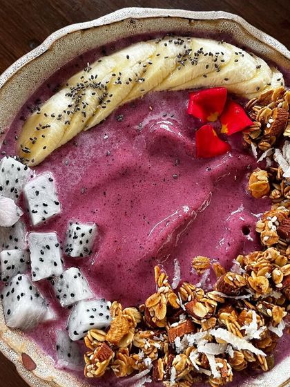 A vibrant smoothie bowl topped with fresh fruit and granola. This top down shot is full of color and texture, making it look both healthy and delicious. A perfect shot for a health cafe.