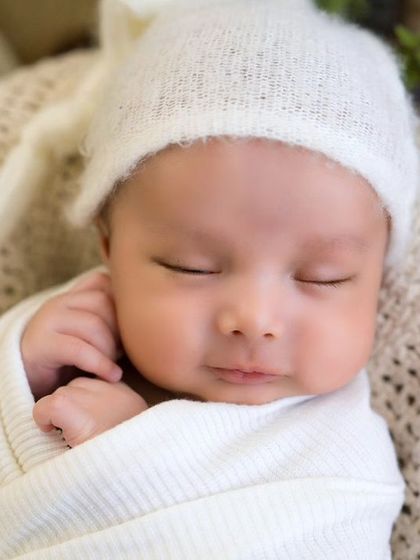 A peaceful, sleeping newborn wrapped in soft white. This close-up shot captures the serene beauty and innocence of a brand new baby.