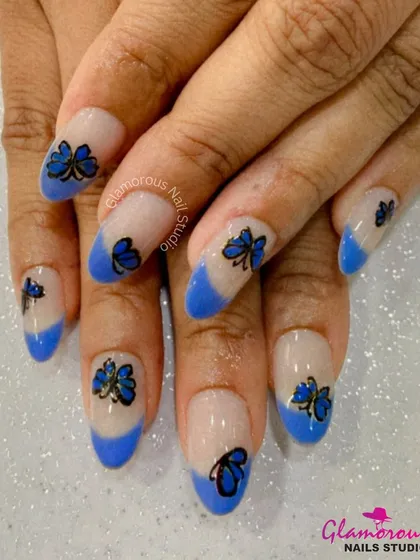 A creative take on a French manicure, this design features blue tips and delicate black butterfly outlines on a sheer base.
