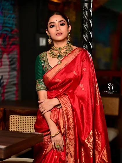 Actress Ishaa Saha in a radiant red saree for Onnosomoy newspaper. The full-length shot against a modern, artistic background creates a beautiful contrast between traditional attire and contemporary art.