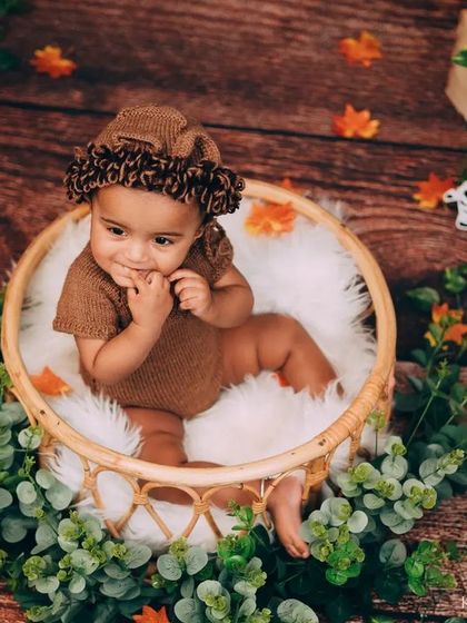 A sweet, shy smile from this baby nestled in a basket. The autumn leaves and soft textures add warmth and detail to this woodland-themed baby photoshoot.
