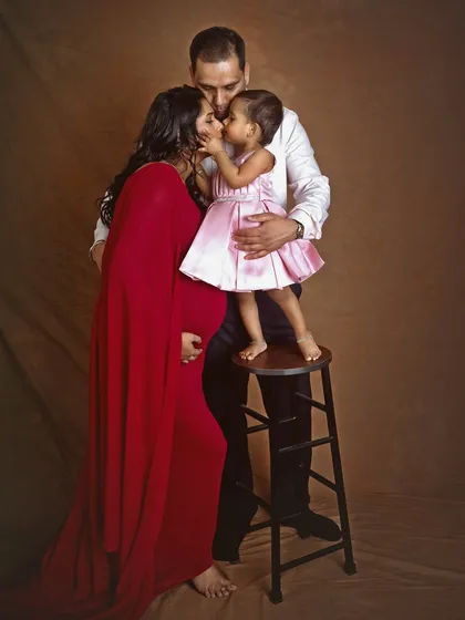 A precious moment as the little girl stands on a stool to give her mother a kiss. This image is a perfect example of how I incorporate family members to create authentic and emotional portraits.