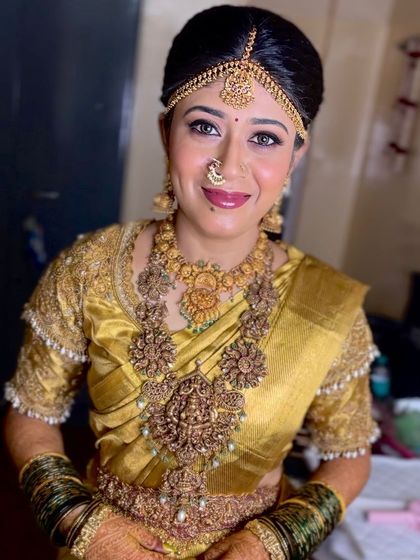 A close up of a beautiful bride in a gold saree. Her makeup features a subtle nose ring, defined eyes, and a warm, glowing complexion for her wedding day.